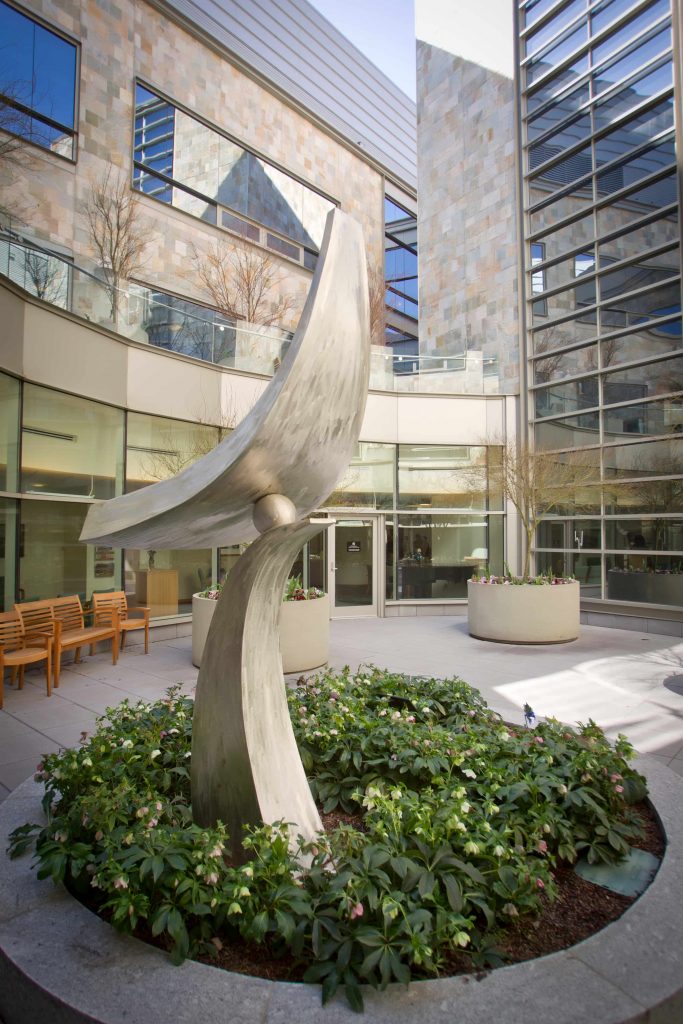 Metal sculpture in the interior courtyard of the N.C. Cancer Hospital. The sculpture is two flat curved pieces balanced between a ball.