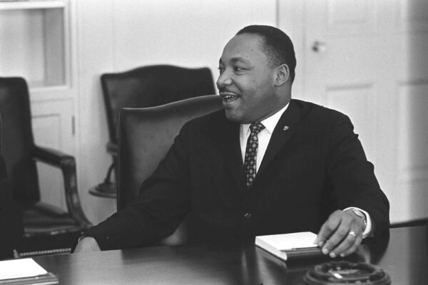 Martin Luther King Jr. talking and smiling at his desk.