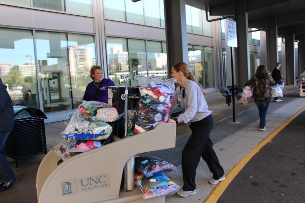 Kelly Kivette (right), senior recreational therapist at UNC Hospitals, helps to unload hats, scarves and blankets for delivery to patients in the Bone Marrow Transplant Unit.