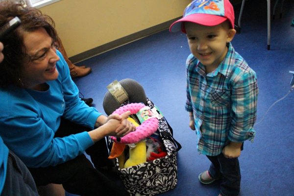 Elizabeth Stewart helped three-year-old Mary Harper Edsall pick a hat. Stewart and a team of volunteers delivered new hats and other items to patients in the N.C. Cancer Hospital pediatric clinic as well as to cancer patients in other clinics.