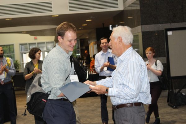 Jesse R. Raab, PhD, accepts an award for his poster presentation at the 40th annual Postdoc-Faculty Research Day from Joseph Pagano, UNC Lineberger director emeritus, the Lineberger Professor of Cancer Research Professor, and training program director.