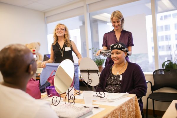 Zulaika Vesovski looks into the mirror and Benvinda Muinde looks on as Amy Kimmy and Gail Markland (center left) demonstrate how to wear scarves, hats and other head wear as part of the American Cancer Society's "Look Good, Feel Better" program.