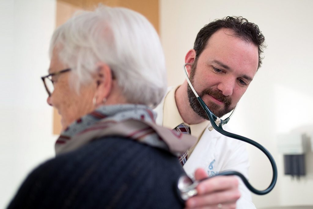 Sascha Tuchman uses a stethoscope on a patient's back