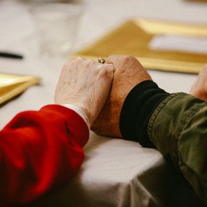 Two people holding hands at a luncheon table.