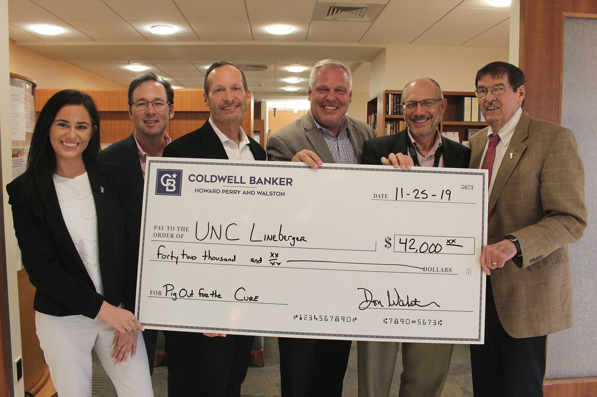 Coldwell Banker Howard Perry and Walston real estate agents presenting a check for $42,000 to the UNC Lineberger Comprehensive Cancer Support Program