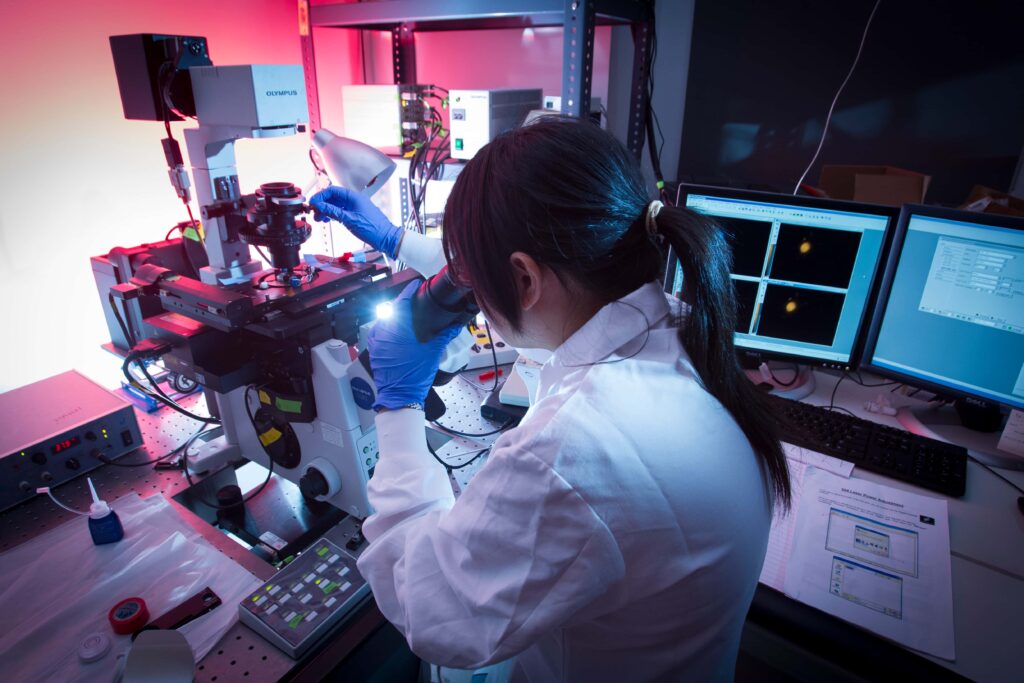 A researcher looks through a microscope in a lab