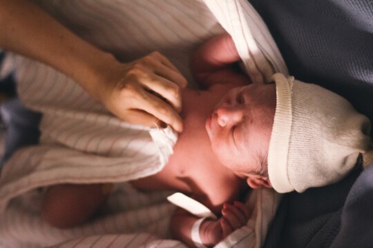 Person covering newborn infant with a swaddling blanket