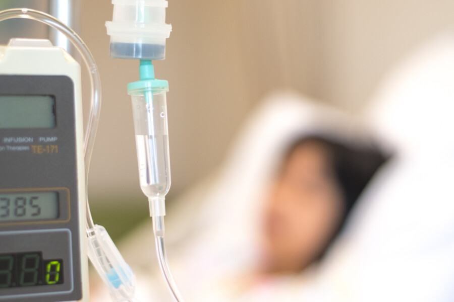 Person in a hospital bed with an IV drip