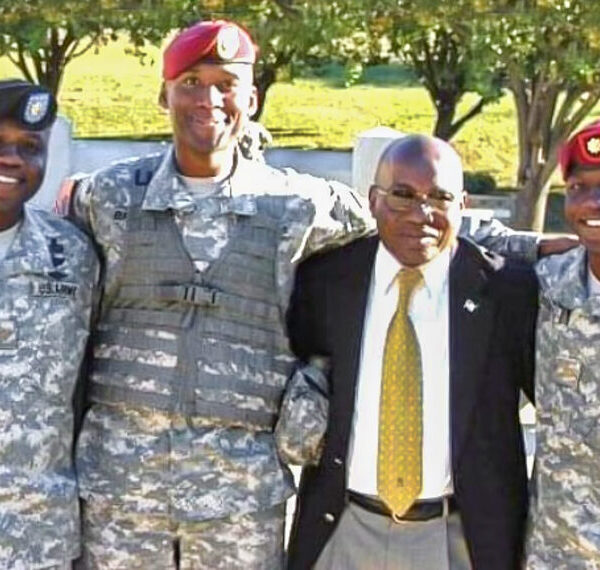 Albert Brunson, wearing a suit and tie, stands with three men wearing military uniforms.