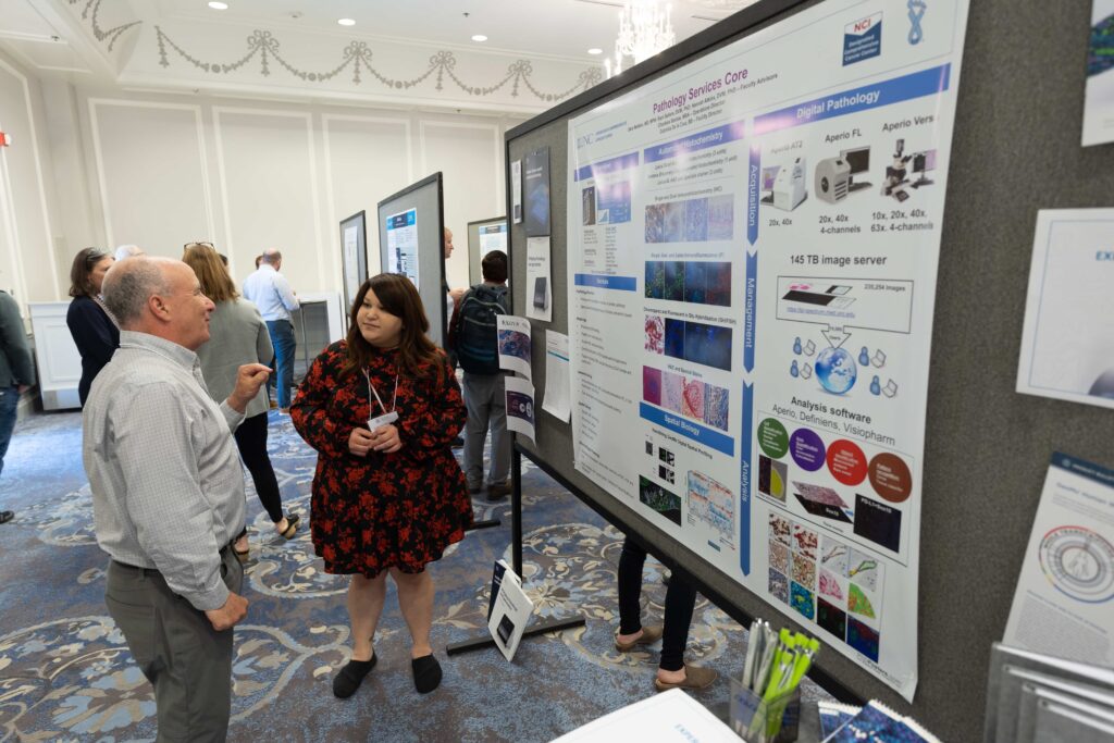 Two people gather around a scientific poster and discuss the Pathology Services Core Facility