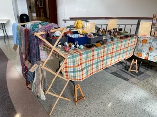 Table with handmade crafts, including scarves and pottery.