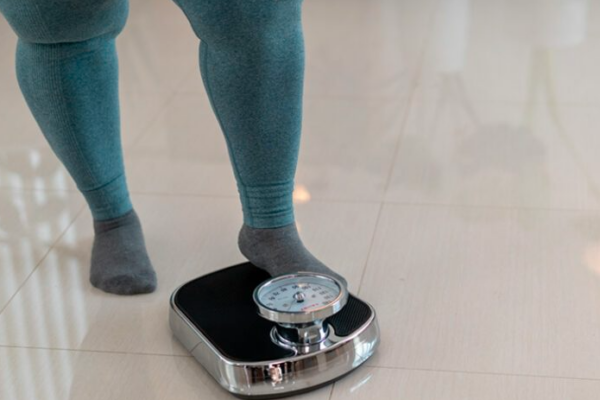 A person steps onto a scale to measure their weight.