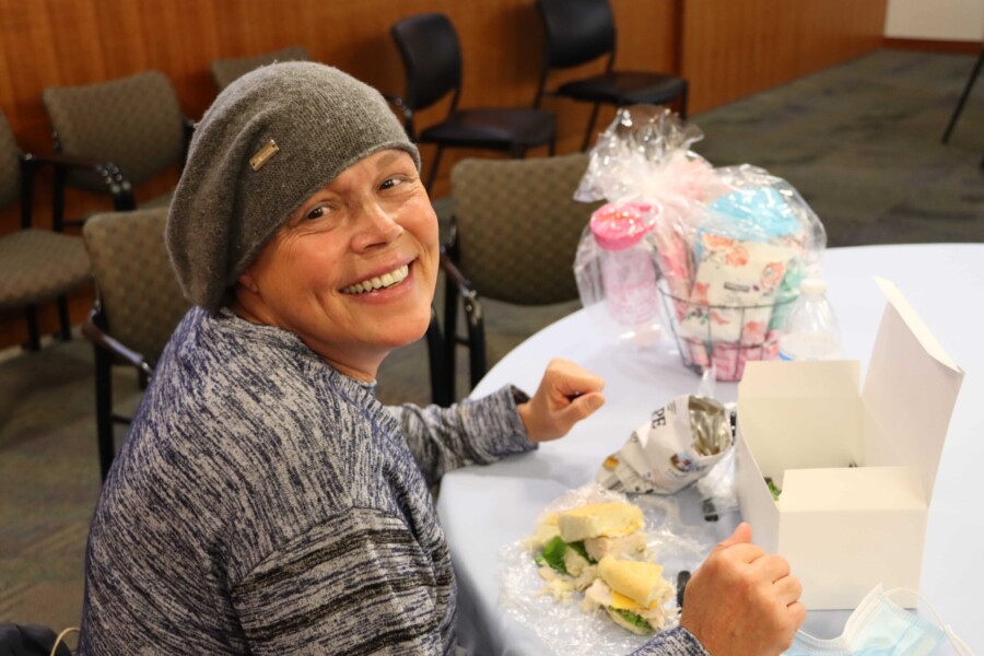 A smiling person enjoying a boxed lunch from the cancer hospital's Thanksgiving luncheon for patients and caregivers.