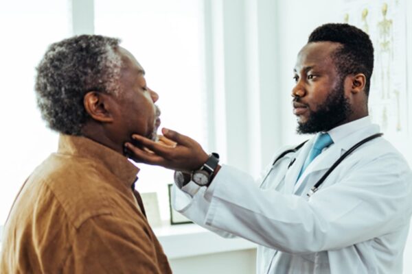 A physician examining a male patient in a clinic room.