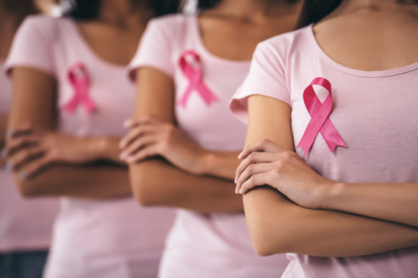 Women wearing pink t-shirts with a pink ribbon pinned to their shirts.