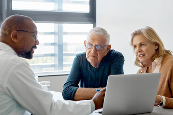 A patient and caregiver meet with a radiation oncologist to discuss a treatment plan.